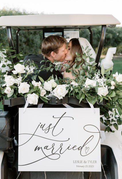 photo of bride and groom with just married sign and a golf cart